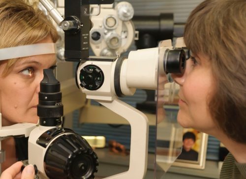 Close-up of two women engaged in an eye exam using an ophthalmic device.